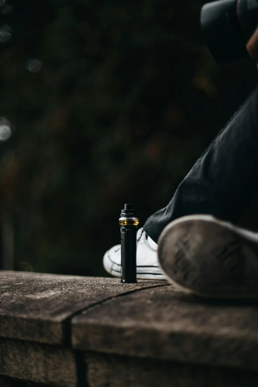 a person holding a camera while a vaping device is next to them