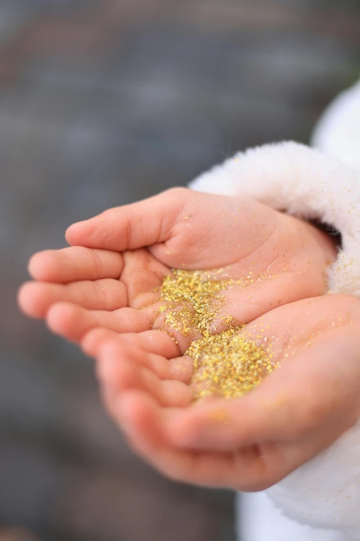 a person holding yellow glitter inside their hands