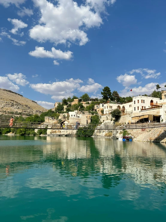 a body of water that has some buildings on the shore and green trees on top