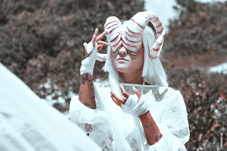 a girl with white makeup and horns is posing