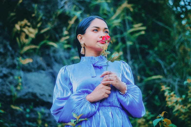 a woman in a blue dress blows a flower