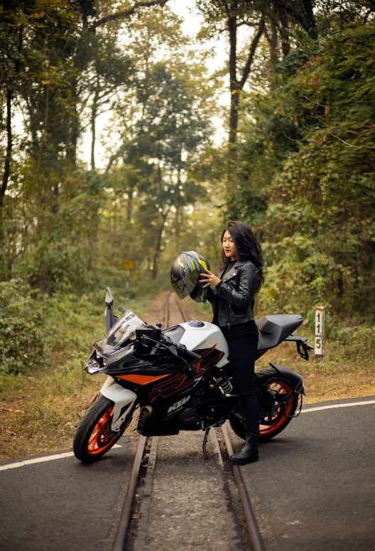 a woman sitting on a motorcycle next to the train tracks
