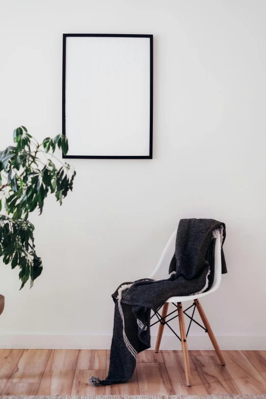 a wooden chair near a plant and large picture frame