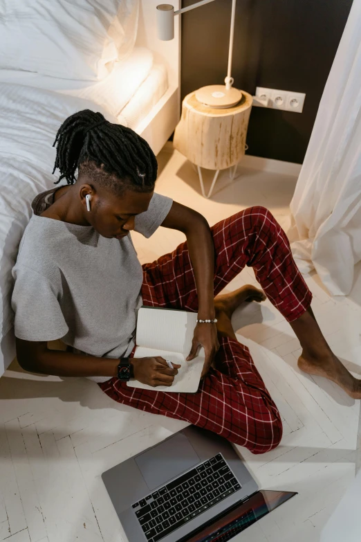 a woman with dreadlocks is sitting on a bed and using a laptop