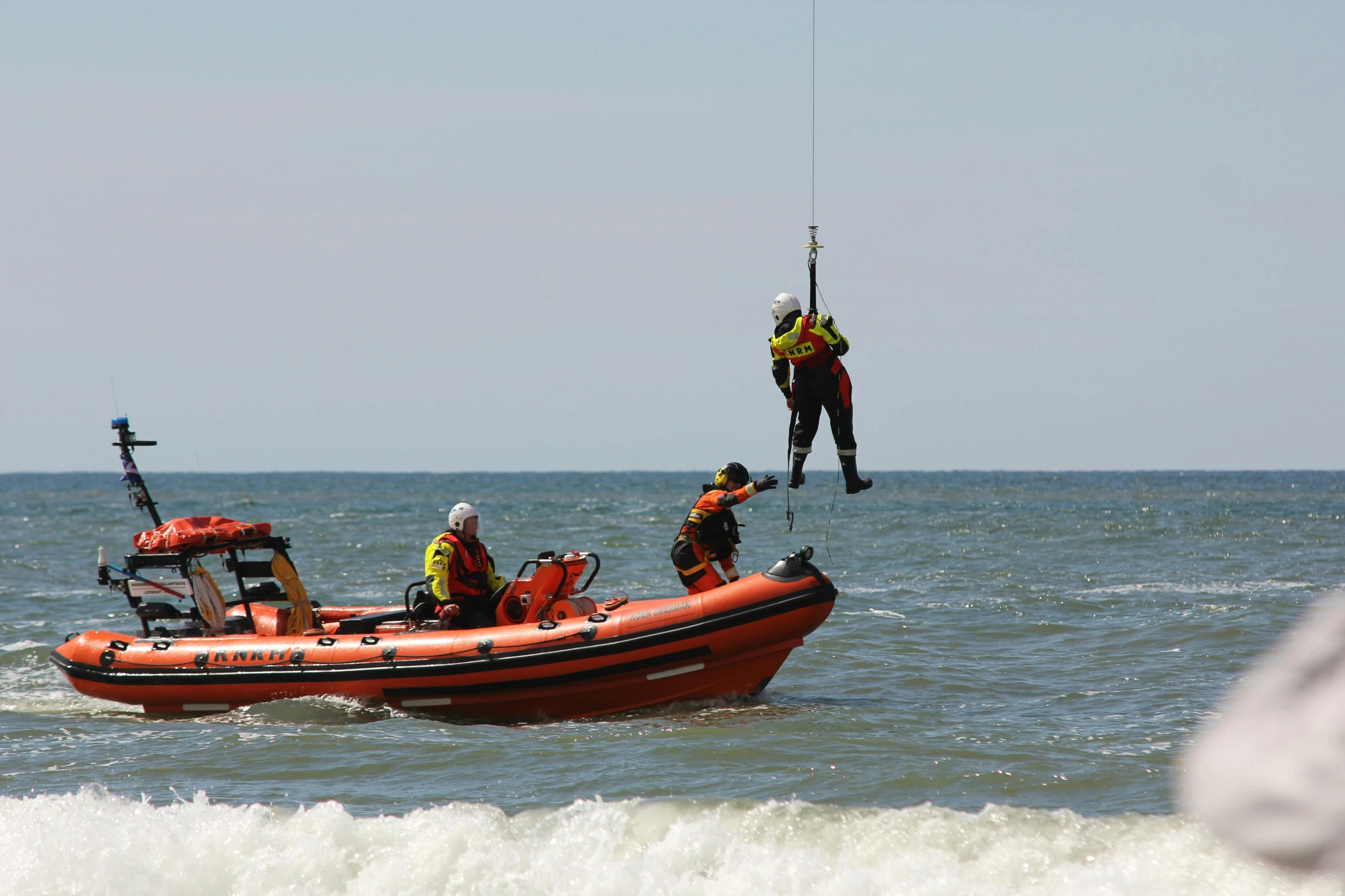 three people hanging off of an inflatable raft on the ocean