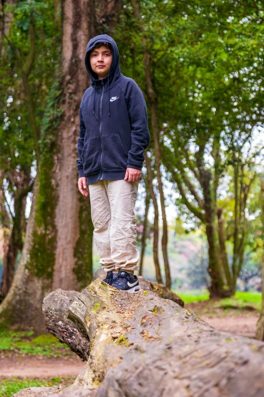 a young man posing on the edge of a fallen tree