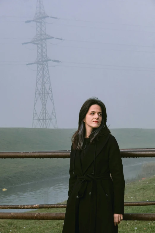 the woman is standing near a power line on a foggy day