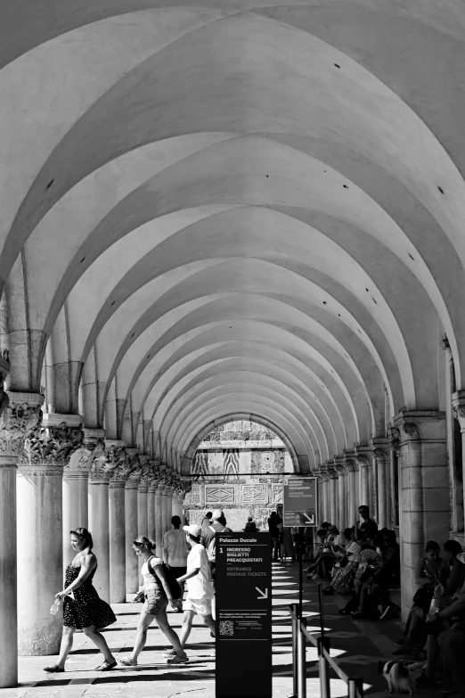 people sitting on benches underneath large arches in an arched, open area