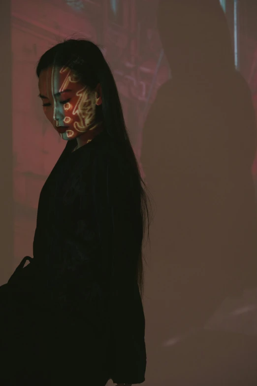 a woman wearing a mask and black clothes in front of a projection on a wall