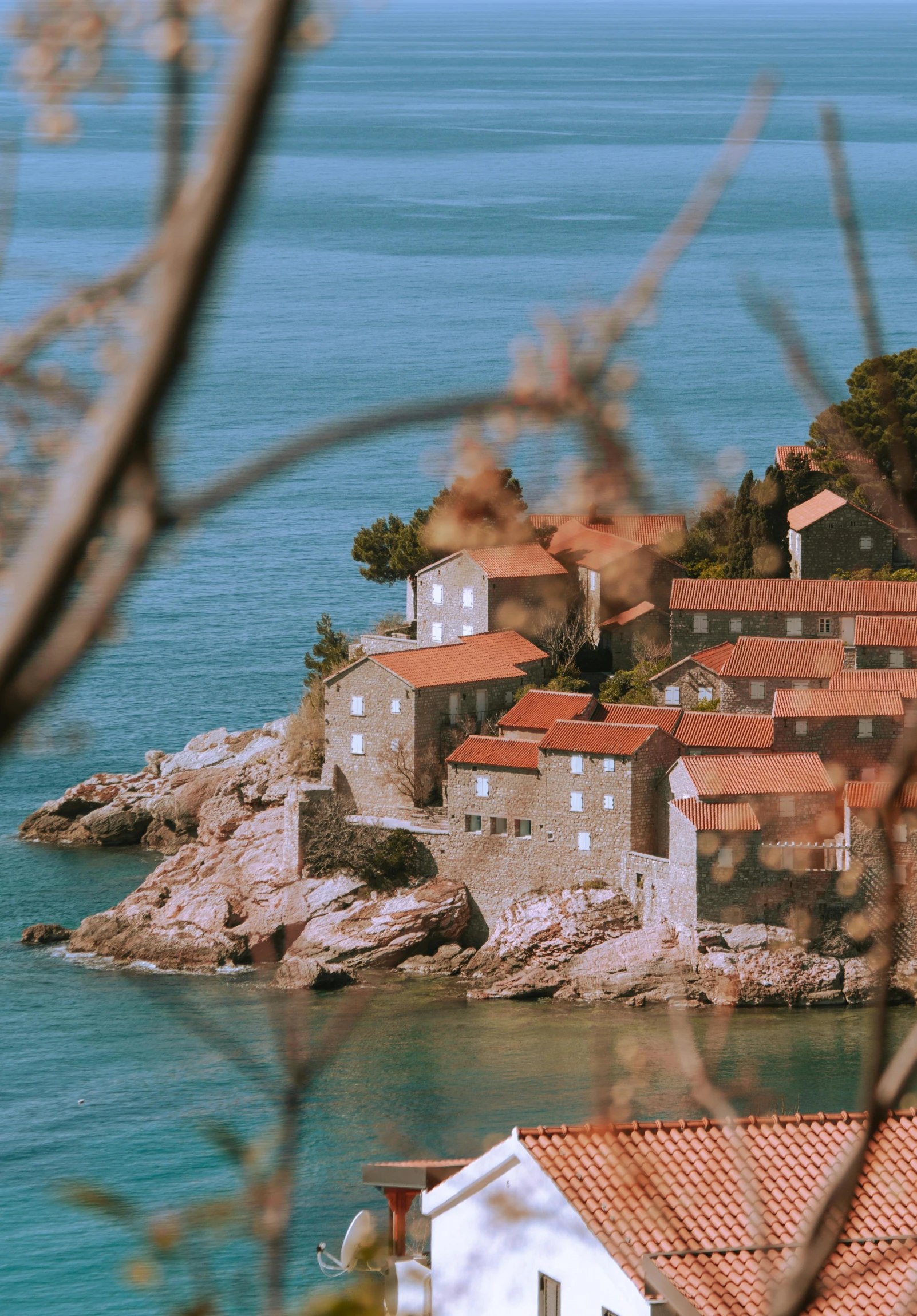 an old town with red tile roofs overlooks the ocean