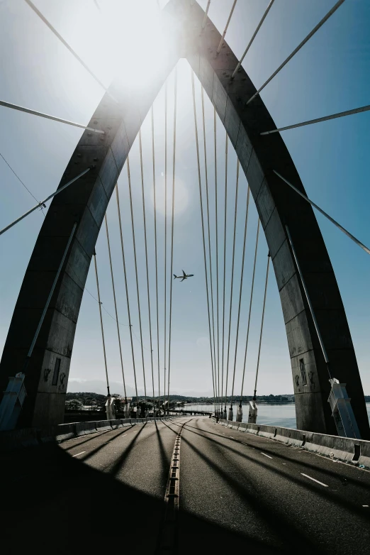 the view from underneath the bridge, looking at an airplane flying through the blue sky