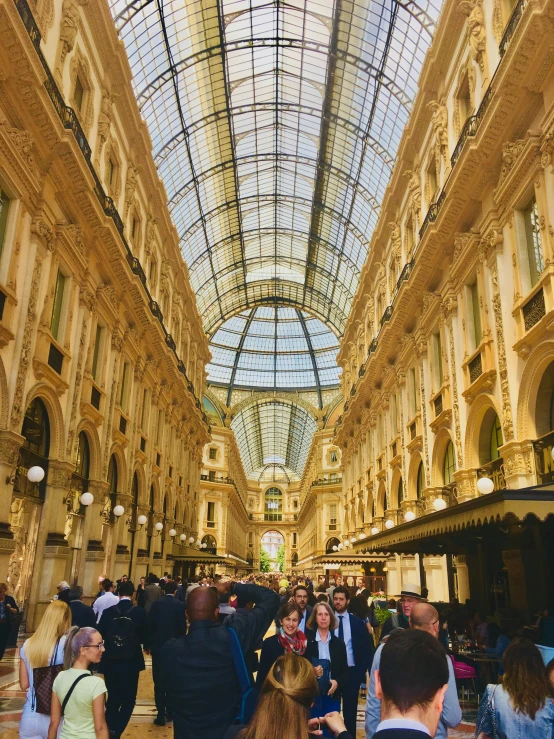 a mall filled with lots of people with tall buildings behind it