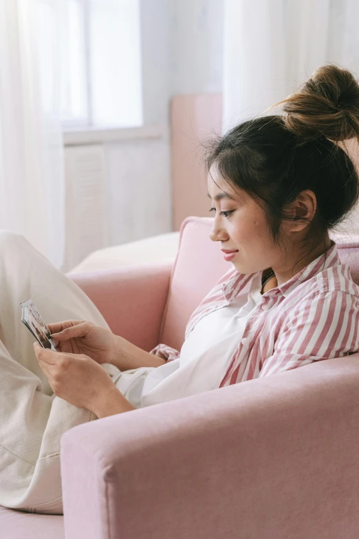 woman sitting on a pink couch with a smart phone