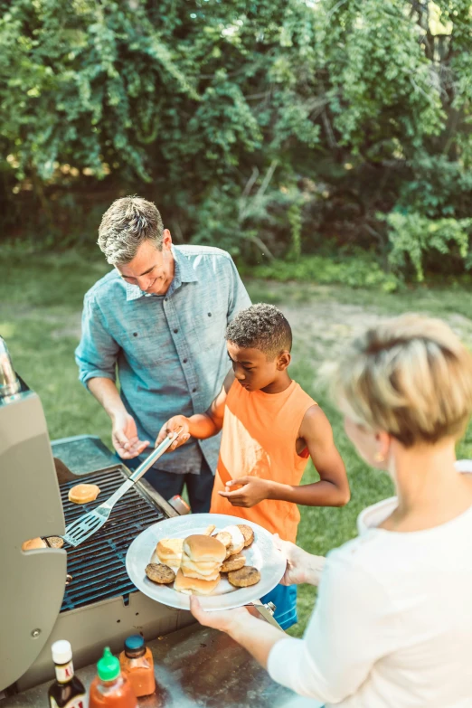 there are people and a woman cooking hamburgers on the grill