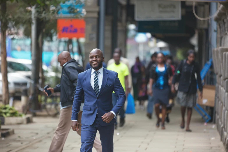 an african american man is smiling while walking down the sidewalk