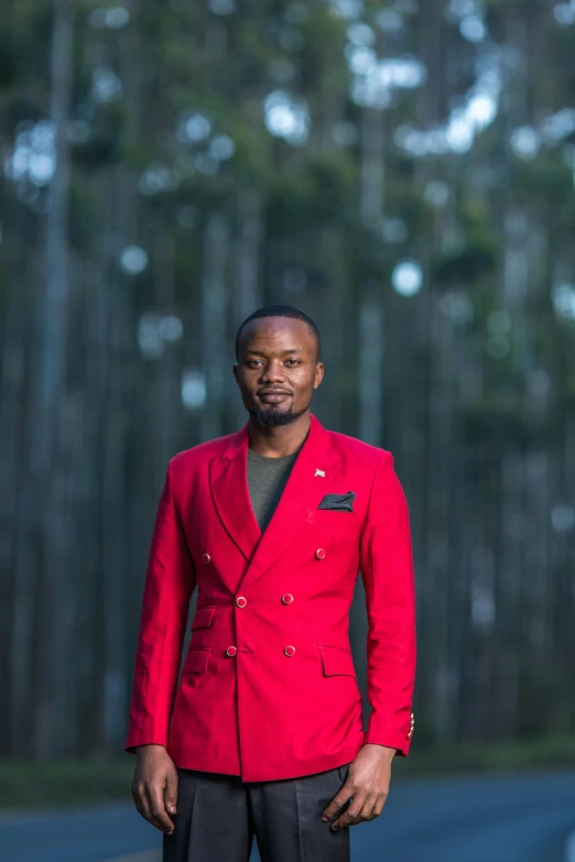 a man in a red jacket standing next to some trees