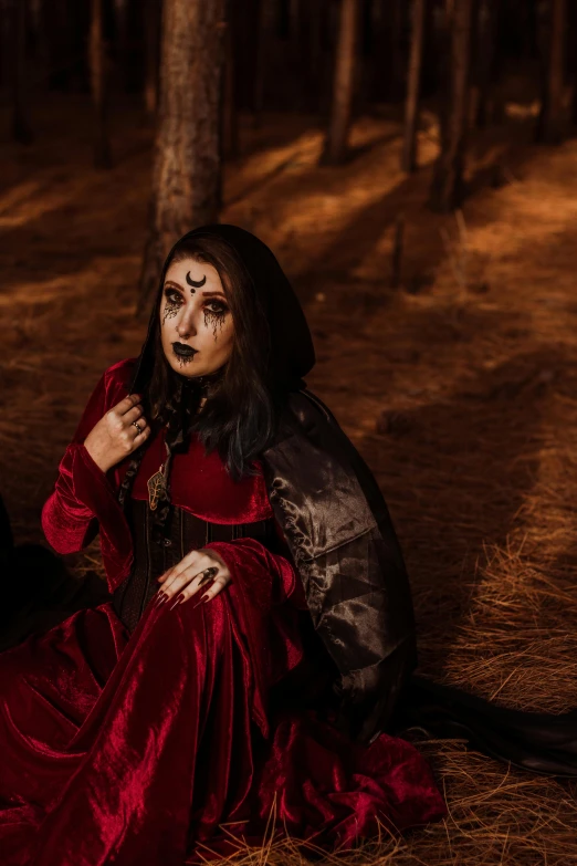 a woman with a face painted in red sits on the ground