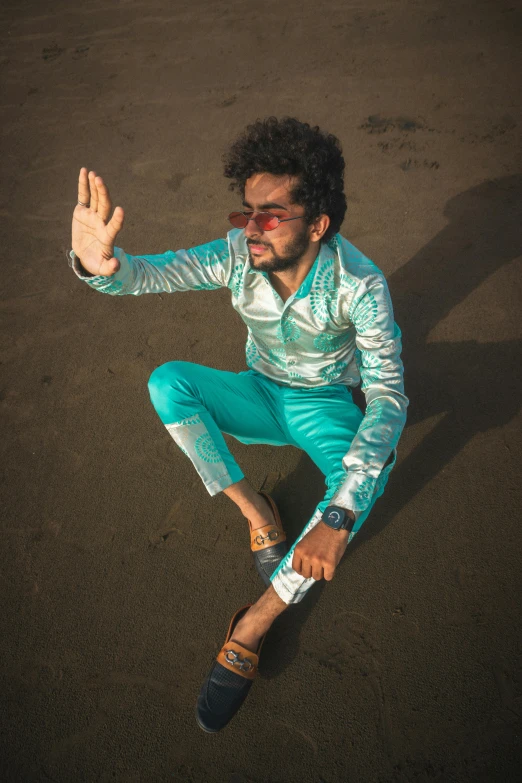 a male in a suit and sunglasses sitting on a floor