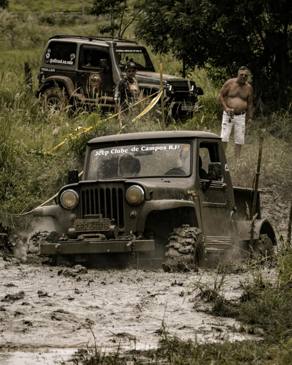 a man is standing next to a jeep in the mud