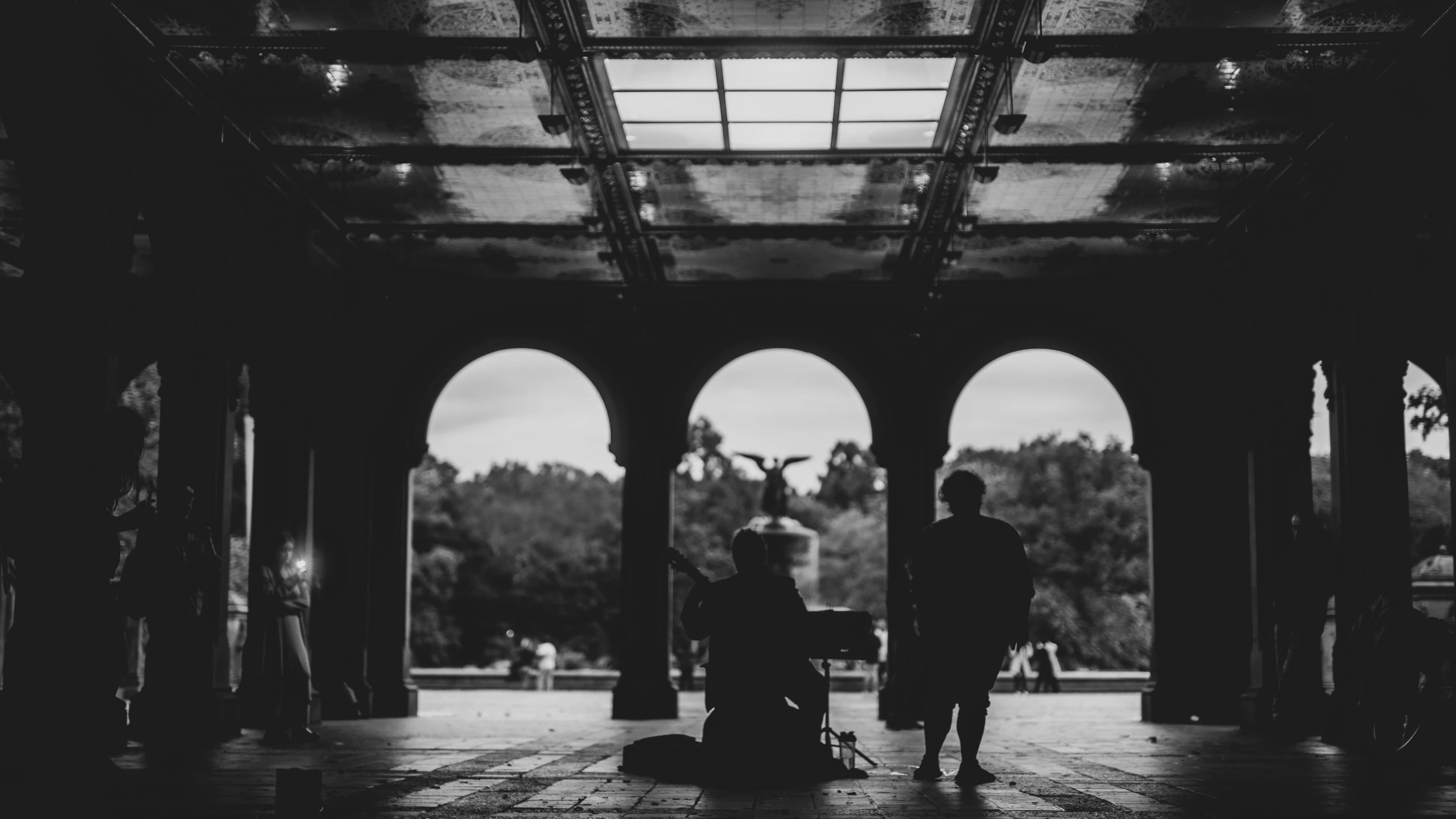 a man standing in a park next to an archway