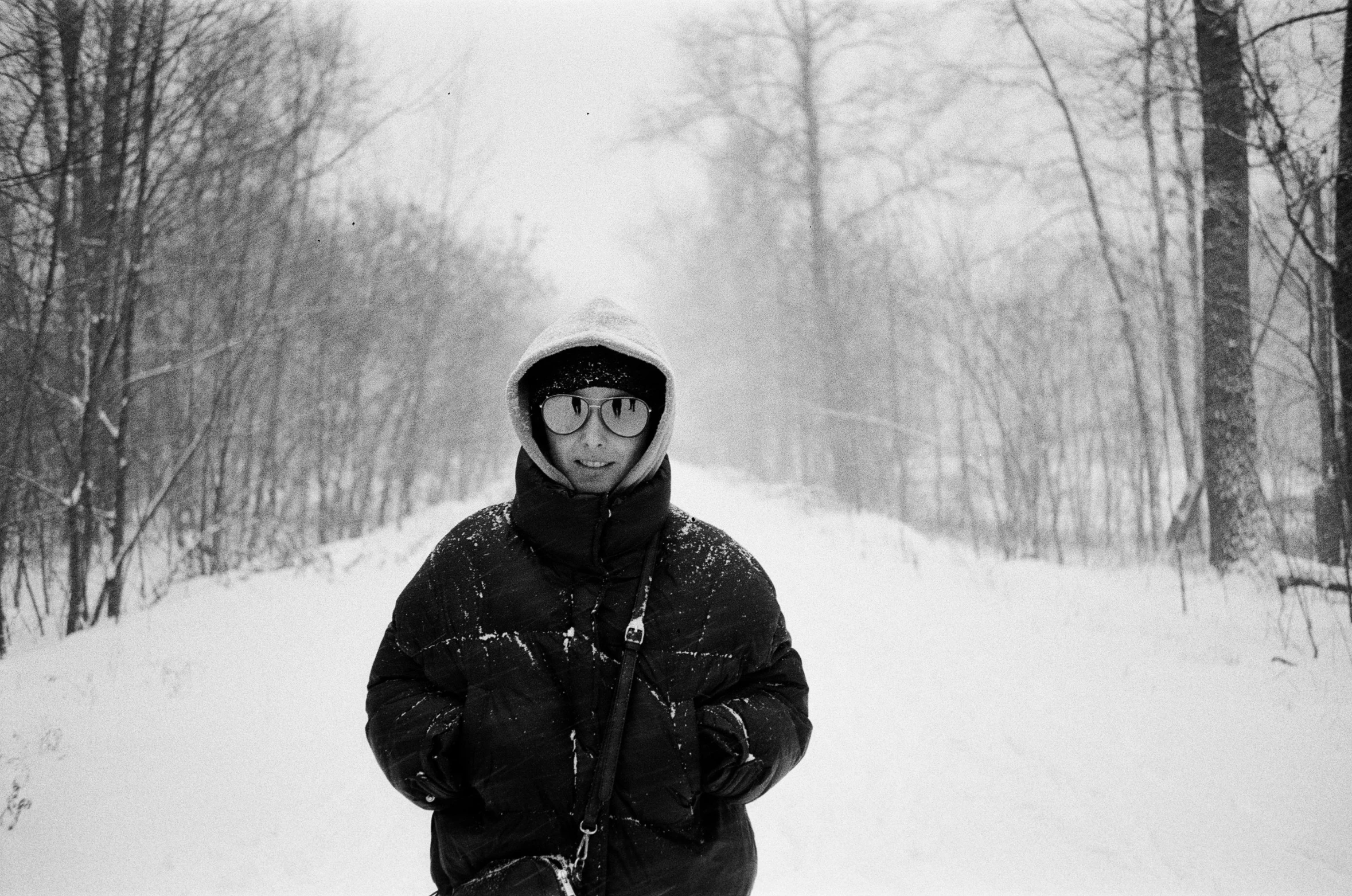 the man smiles while standing in a snowy forest