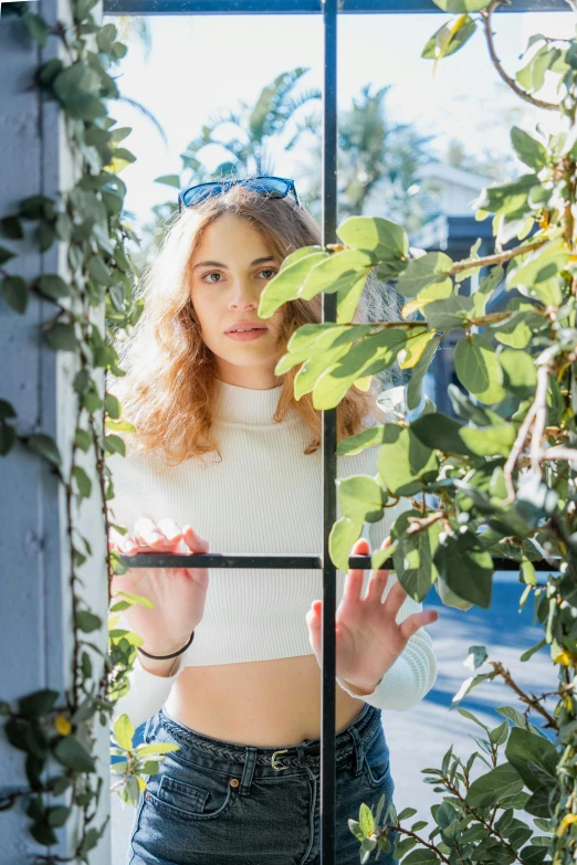 a girl with long curly hair stands looking in through the window