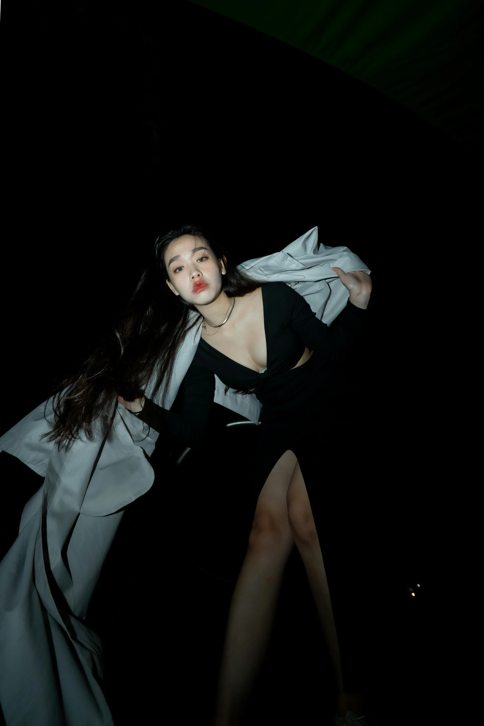 a woman in black dress in dark room with white material