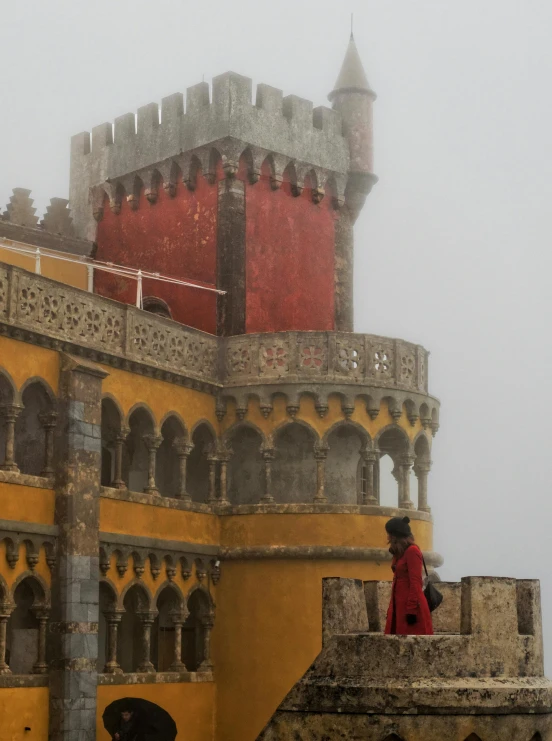 a large castle building has an overhang and a man standing in front of it