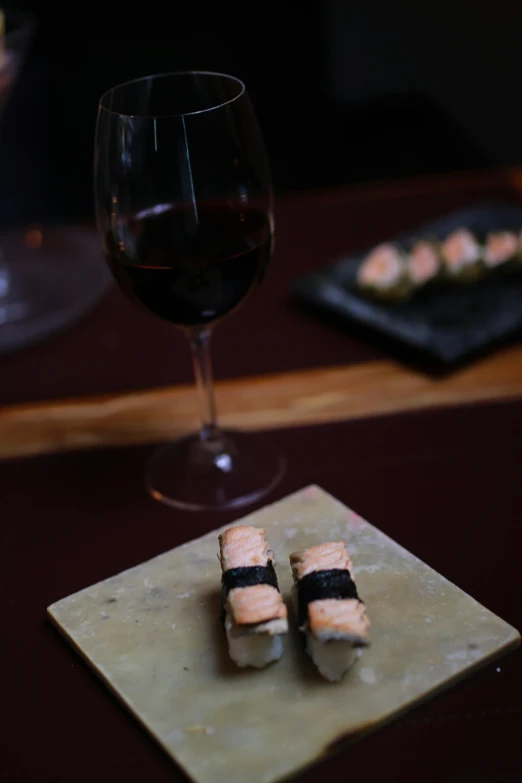 some chopsticks sitting on a brown plate next to a wine glass