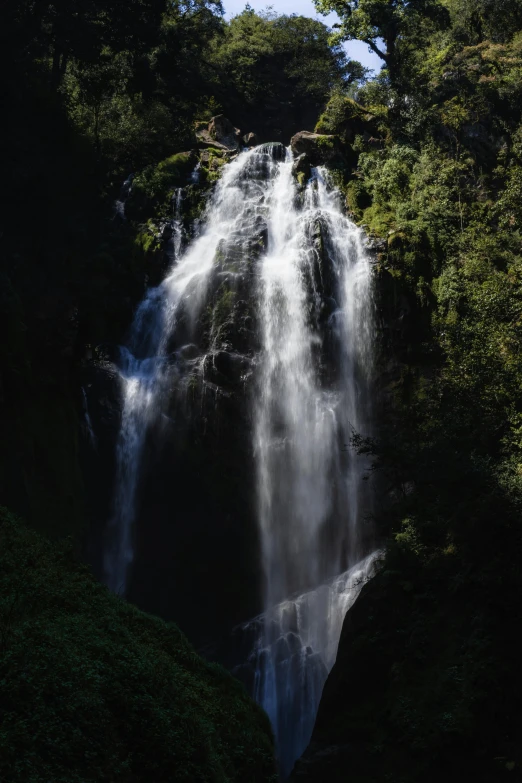 the large waterfall is covered in lush green vegetation