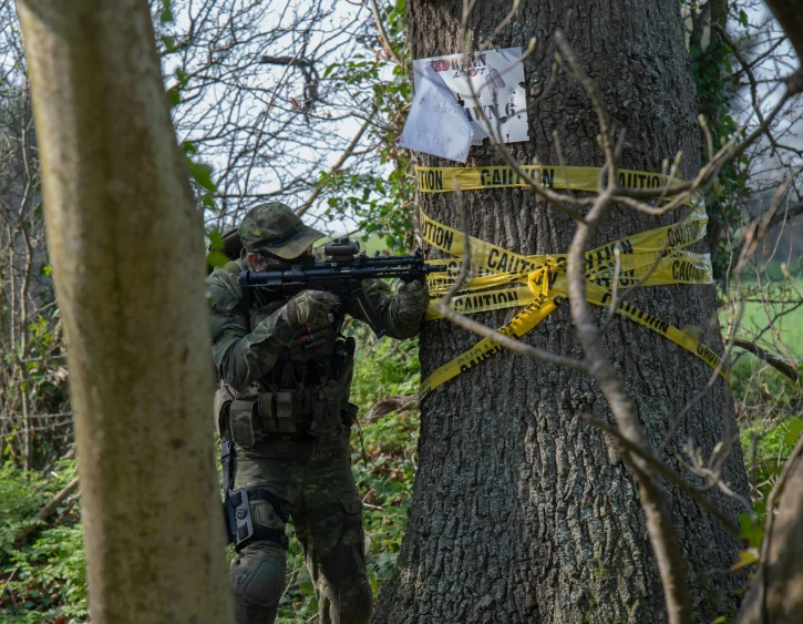 a man holding a machine gun in the woods