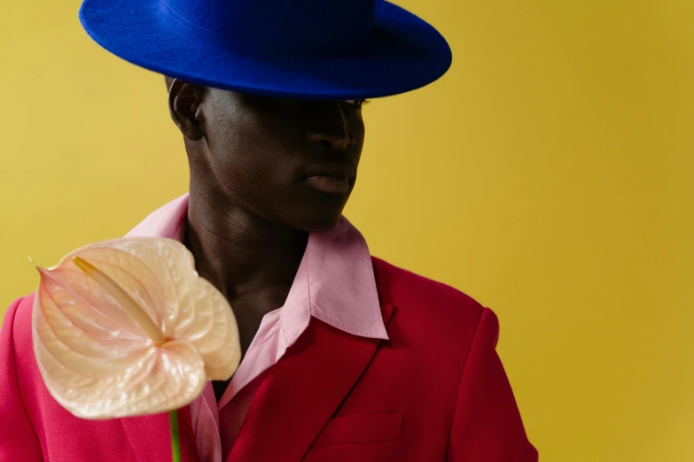 a man wearing a blue hat holds a fake flower