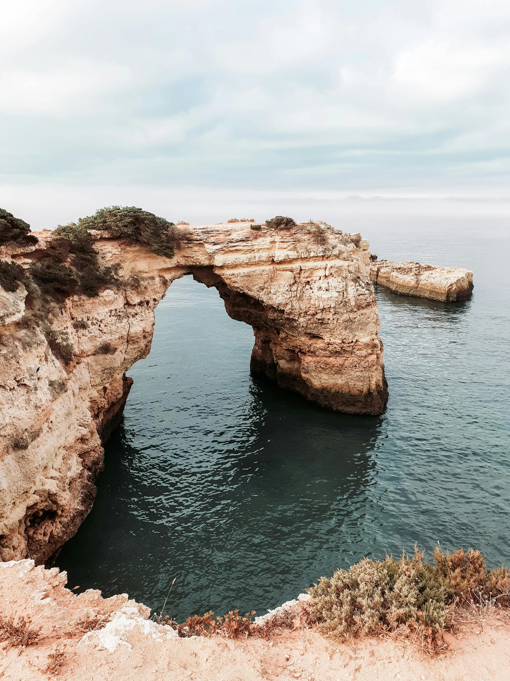 an arch shaped in a cliff next to the ocean