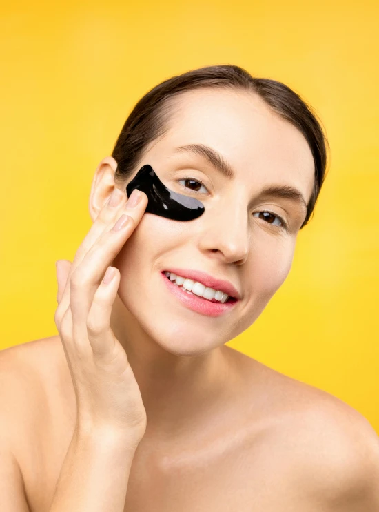 a woman with a black mask holds up a sponge on her face