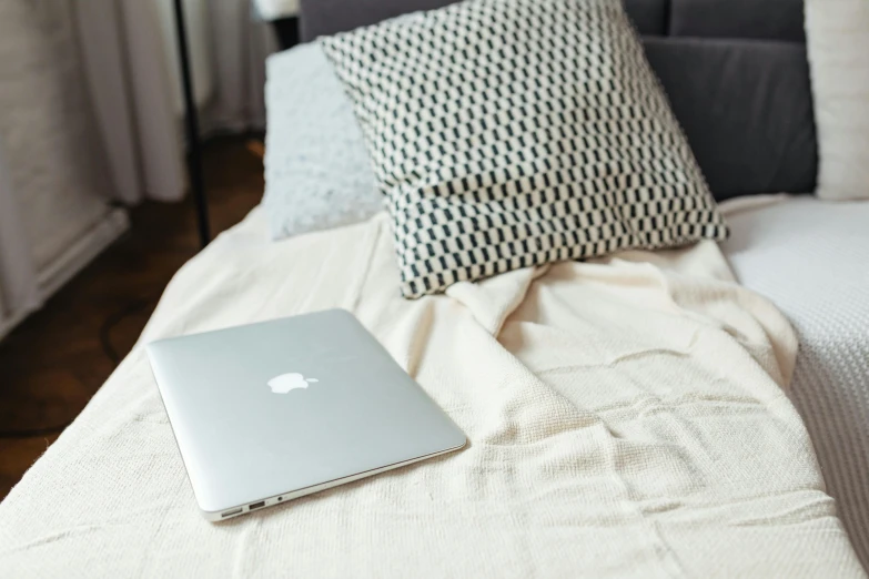 a laptop sitting on top of a bed near a pillow