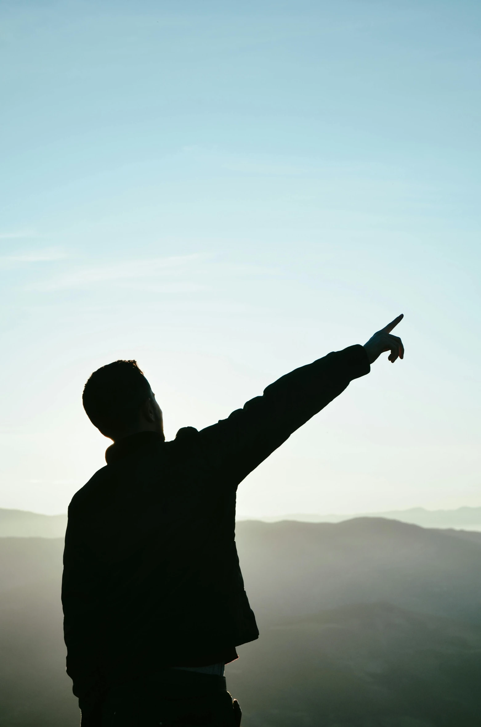 the man is pointing to the sky near mountains