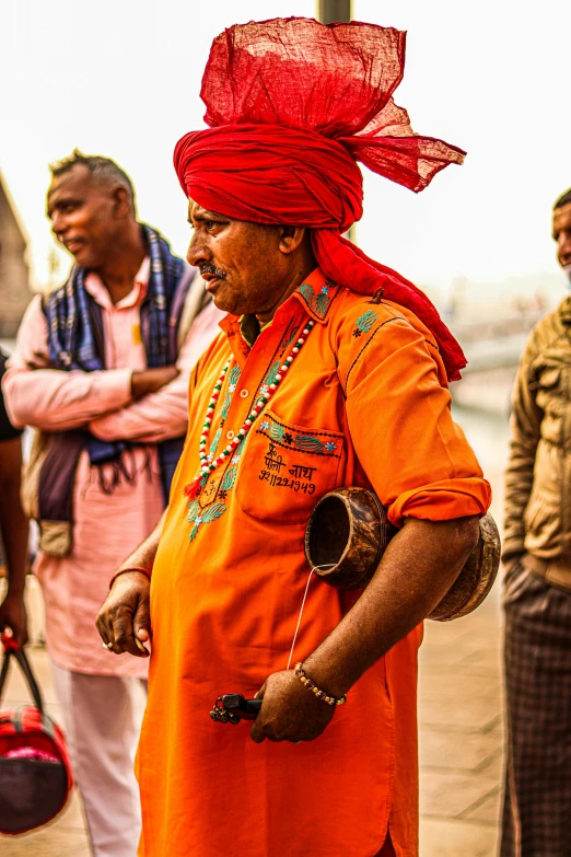 a man dressed in a bright orange outfit holds a camera