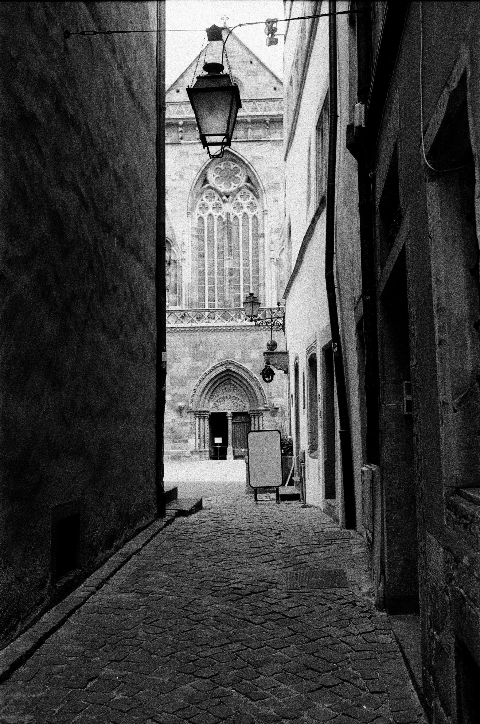 an old narrow alley with a light post and a clock tower