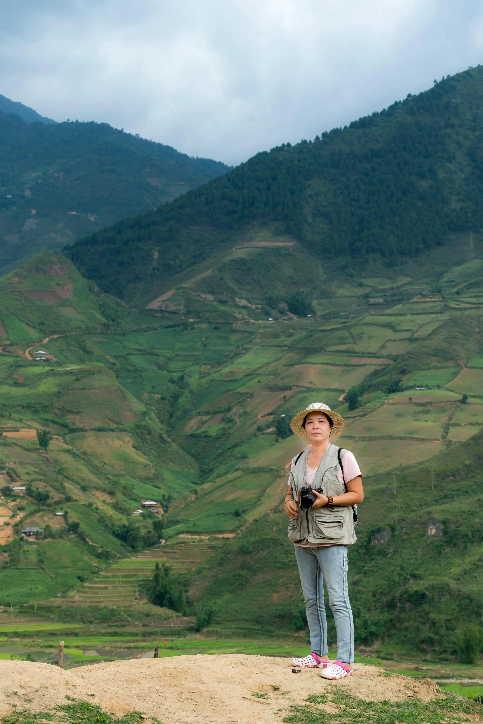 a woman wearing a sunhat on top of a mountain