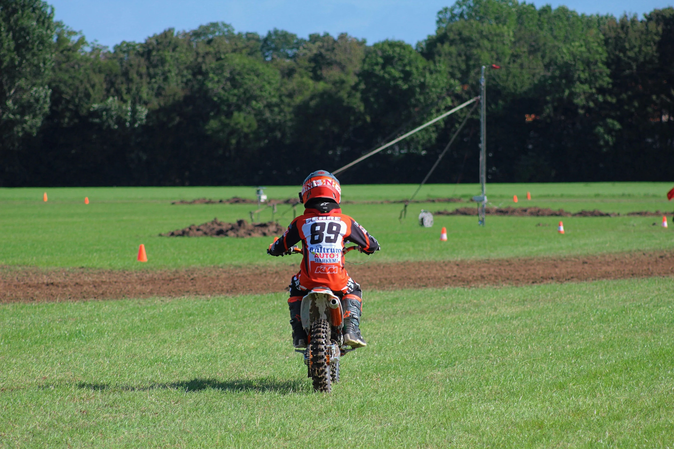 a young man riding a dirt bike across a lush green field