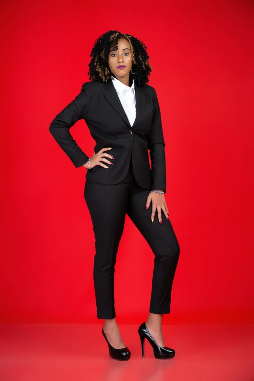 a woman wearing a suit and heels in front of a red background