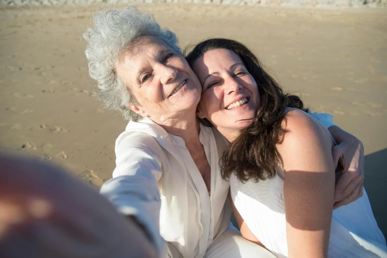 two women are taking a picture on the beach