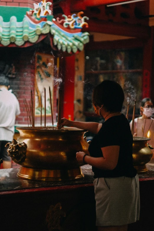 woman in asian restaurant making incense sticks in big pot