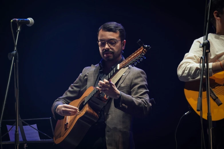 a man playing guitar while wearing a suit