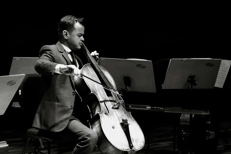 a man playing cello in front of orchestra