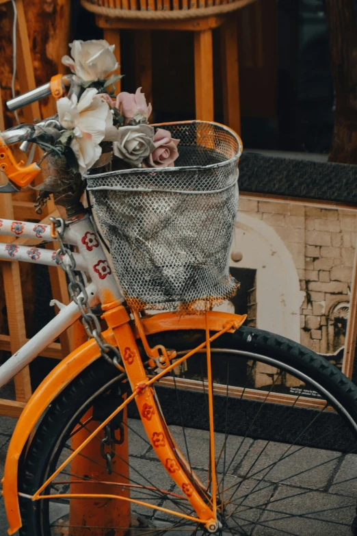 an orange bicycle with baskets full of flowers