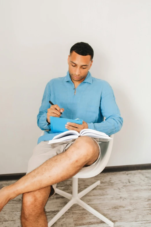 man sitting on a chair writing with his pen