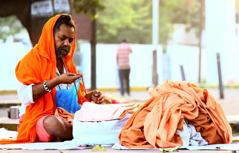 a man sitting down on the ground looking at his bag