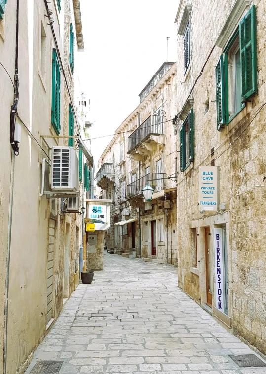 a stone paved street lined with windows and shutters