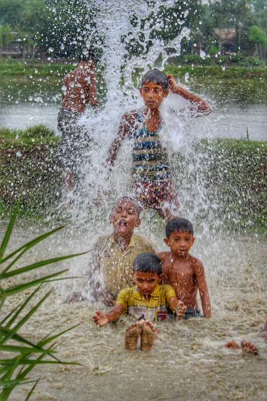 four children splashing in the water while standing in the sand